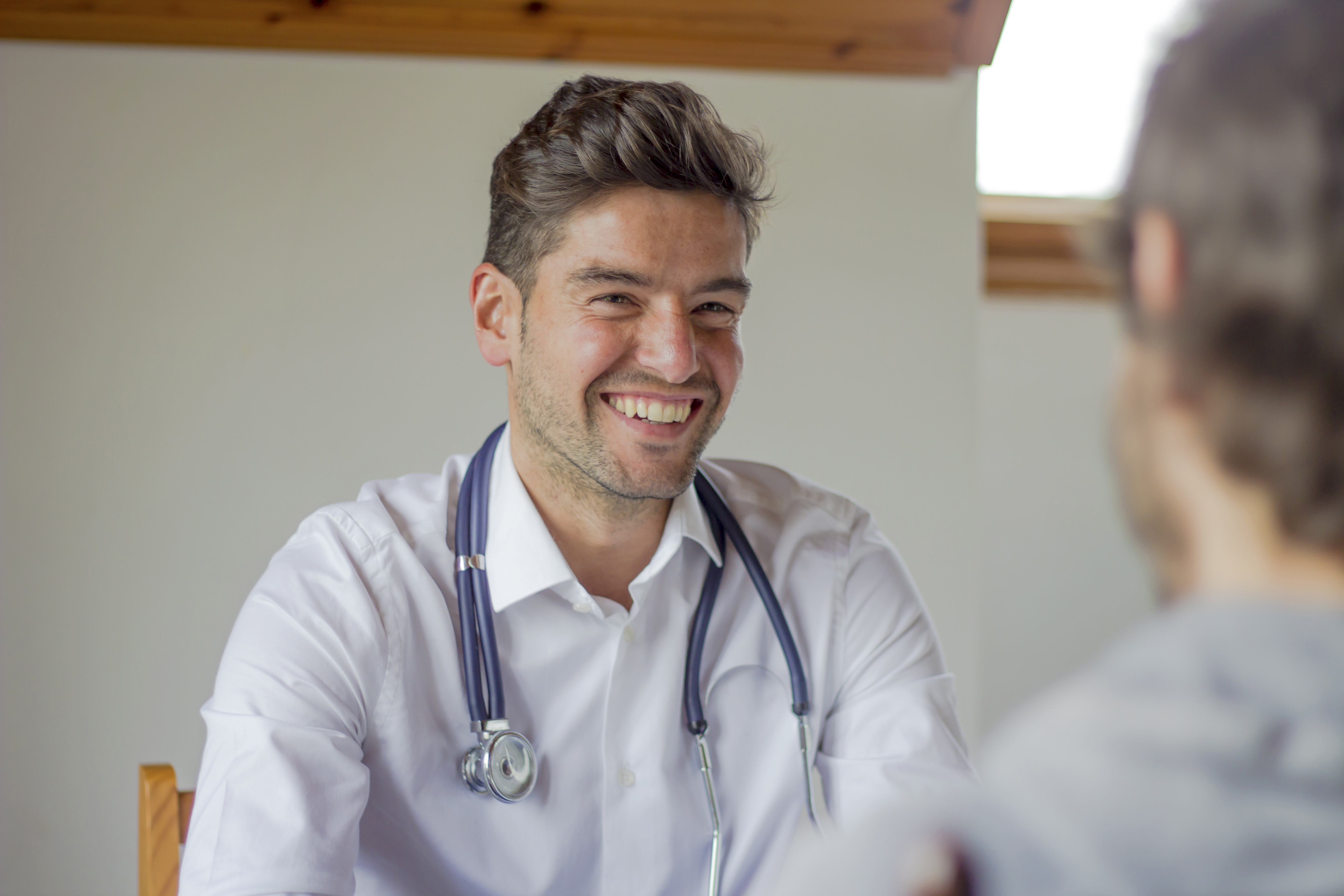 Male GP smiling talking to male patient