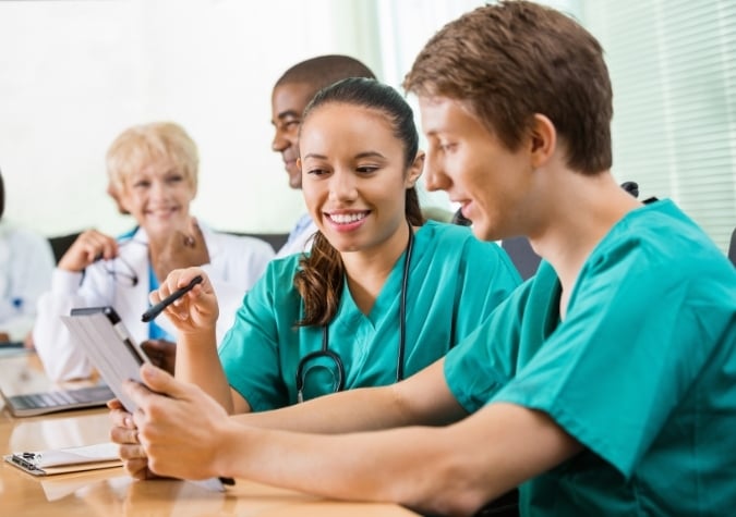 junior doctors in scrubs with tablet