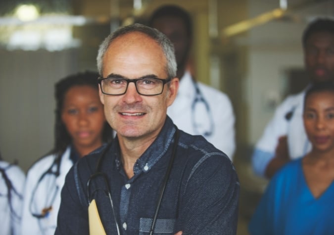 Senior Doctor in dark blue clothes surrounded by other doctors