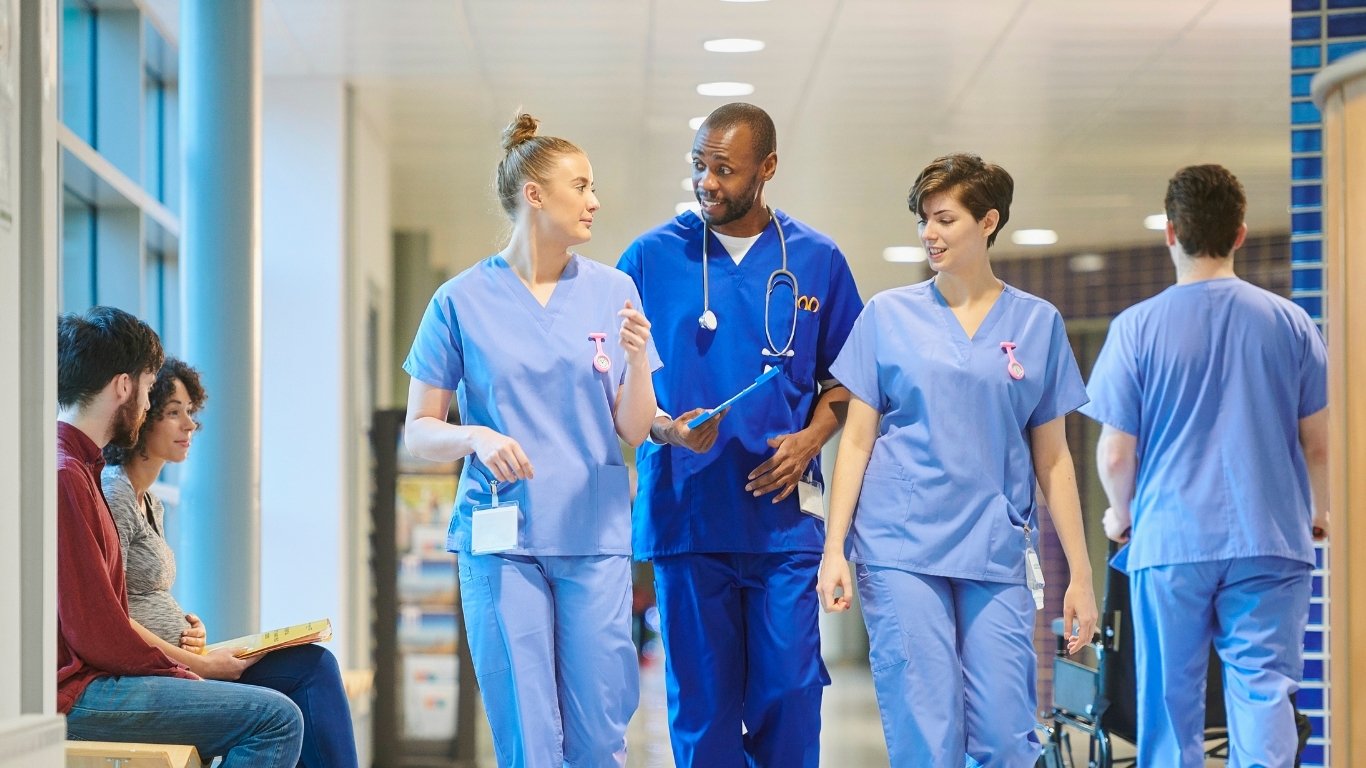 Doctor walking down a hallway in scrubs ith other medical staff