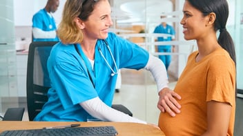 obstetrician with hands on belly of pregnant patient